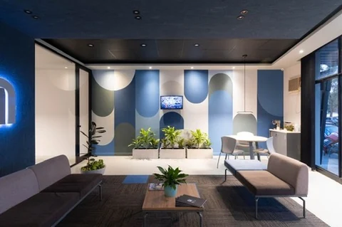 Far wall painted as vertical bands closed with half-circles in blues, greys and cream, echoing the arch of the monogram