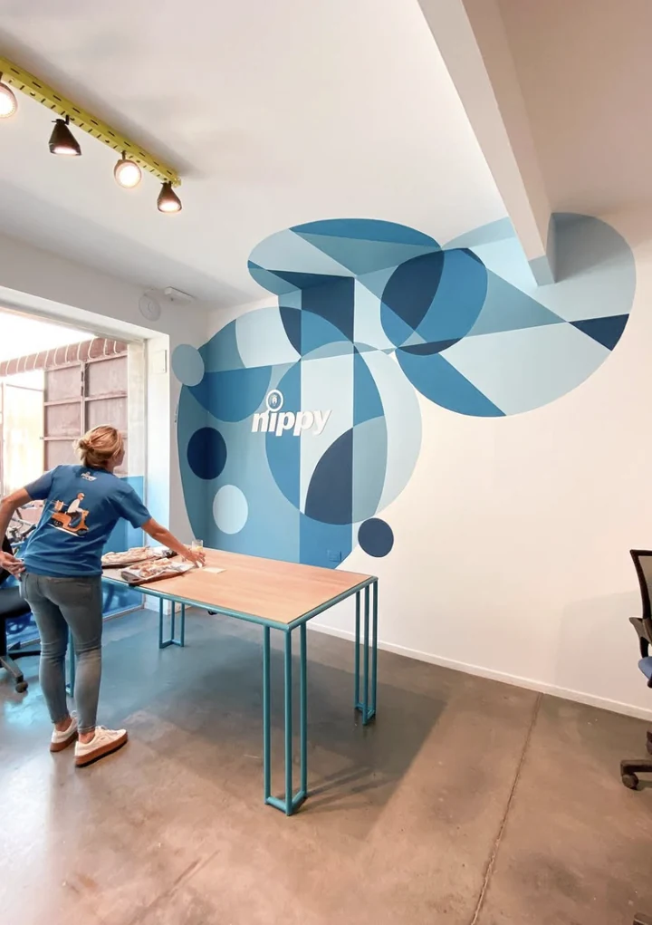 Meeting area with the geometric blue mural continuing behind a work table