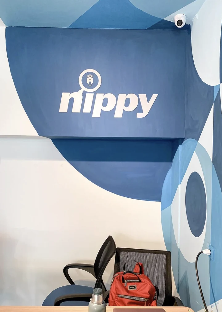 Close view of the Nippy wordmark painted inside the darkest blue field of the mural, where the geometry wraps a soffit